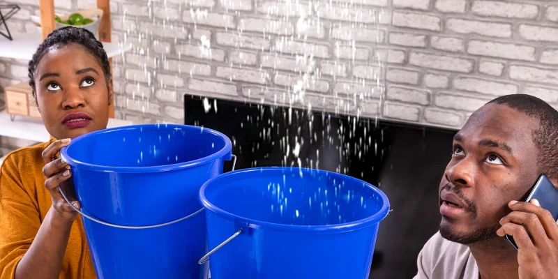 Homeowners catching water from a ceiling leak in blue buckets and calling for emergency plumber in League City